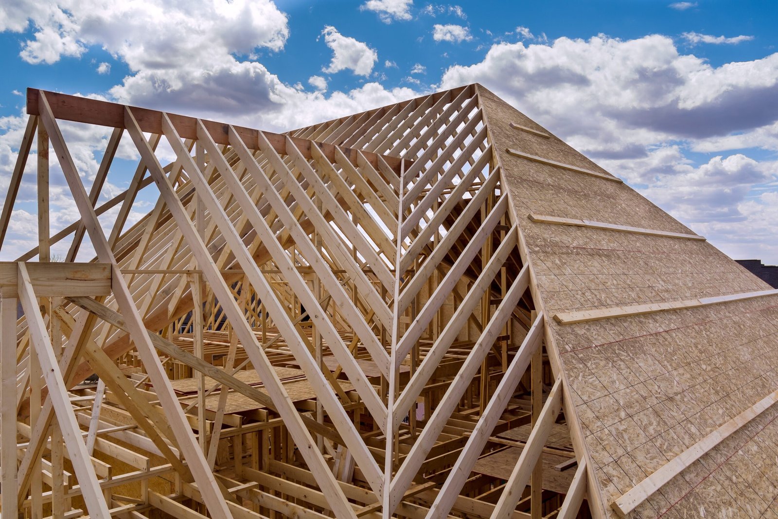 Panorama top view of closeup new wooden roof beams built home under construction under framing with construction site